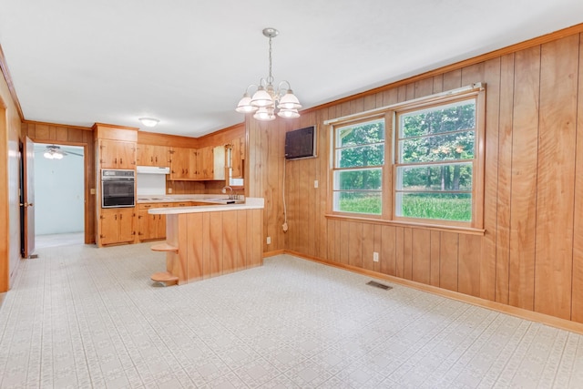 7111 Harrison Dr, Fairview, TN 37062 - kitchen featuring oven, light countertops, a chandelier, wood walls, and a peninsula