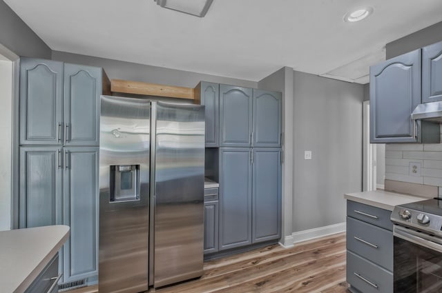 101 Walnut St, Smyrna, TN 37167 - kitchen featuring stainless steel appliances, baseboards, light wood finished floors, backsplash, and light countertops