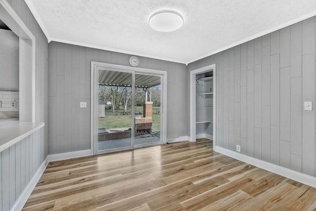 101 Walnut St, Smyrna, TN 37167 - unfurnished dining area with ornamental molding, wood finished floors, a textured ceiling, baseboards, and wood walls