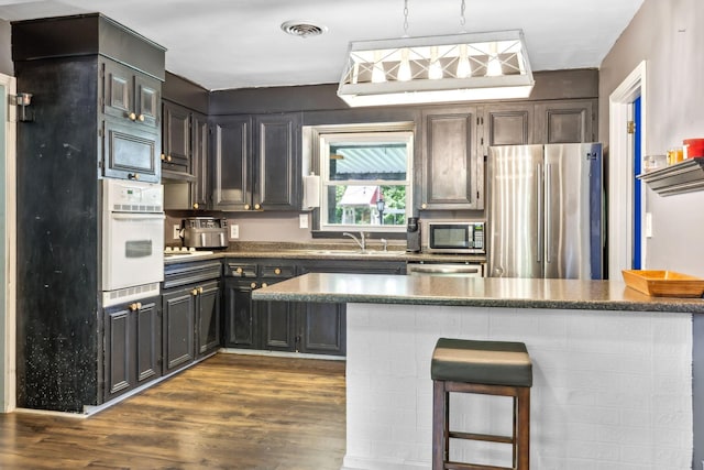 414 Ashe Ave, New Johnsonville, TN 37134 - kitchen featuring stainless steel appliances, a sink, dark wood-type flooring, pendant lighting, and a kitchen bar