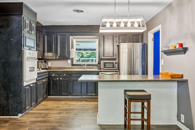 414 Ashe Ave, New Johnsonville, TN 37134 - kitchen with appliances with stainless steel finishes, a sink, wood finished floors, a peninsula, and a breakfast bar