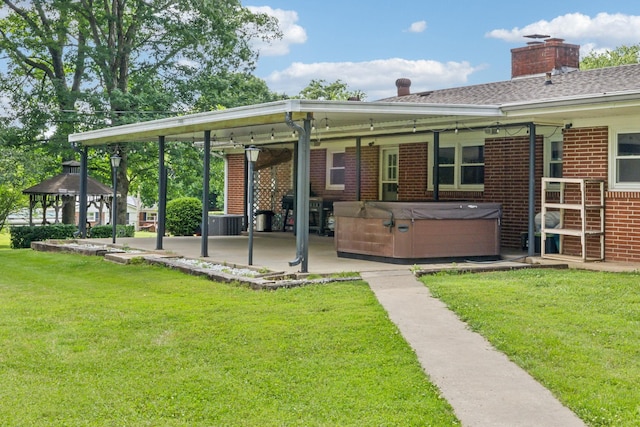 414 Ashe Ave, New Johnsonville, TN 37134 - back of house featuring a hot tub, a patio, a yard, brick siding, and a chimney