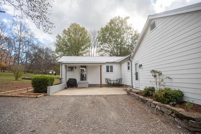 6684 Eudailey Covington Rd, College Grove, TN 37046 - rear view of house featuring a patio, driveway, and metal roof