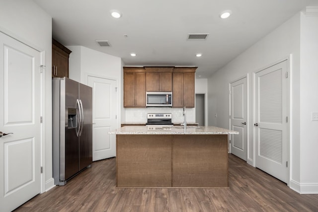 1021 Vida Way Unit 202, Nolensville, TN 37135 - kitchen with appliances with stainless steel finishes, tasteful backsplash, dark wood-type flooring, an island with sink, and light stone counters
