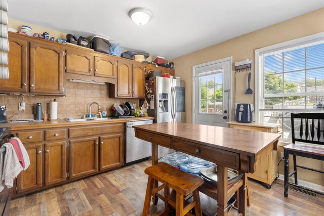 221 Pitts Ave, Old Hickory, TN 37138 - kitchen with appliances with stainless steel finishes, a sink, brown cabinets, light wood finished floors, and backsplash