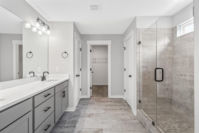 2655 Burton Dr, White House, TN 37188 - full bath with double vanity, wood finished floors, a shower stall, a walk in closet, and baseboards