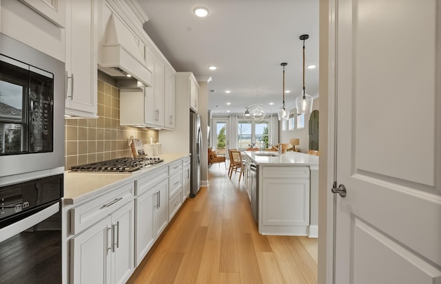318 Sharp Way, Murfreesboro, TN 37128 - kitchen with appliances with stainless steel finishes, custom range hood, light countertops, light wood-style floors, and decorative backsplash