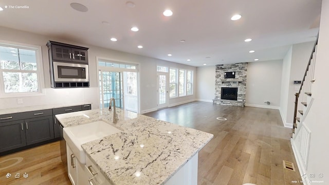 2408 Oakmont Ln, Mount Juliet, TN 37122 - kitchen featuring stainless steel microwave, a stone fireplace, recessed lighting, light wood-style flooring, and a sink