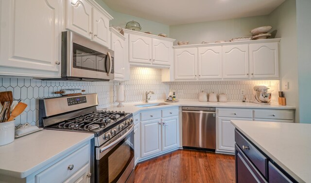 3302 Foxtrot Ct, Spring Hill, TN 37174 - kitchen with stainless steel appliances, a sink, white cabinets, dark wood finished floors, and backsplash