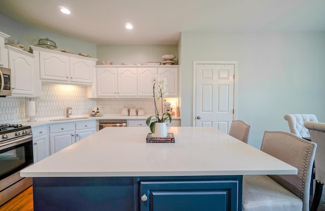 3302 Foxtrot Ct, Spring Hill, TN 37174 - kitchen with stainless steel appliances, a sink, white cabinetry, tasteful backsplash, and a kitchen island