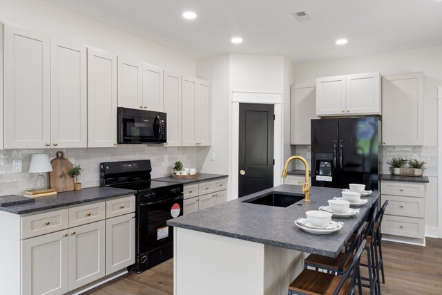312 N Main St, Dickson, TN 37055 - kitchen with black appliances, a sink, dark countertops, backsplash, and a kitchen bar