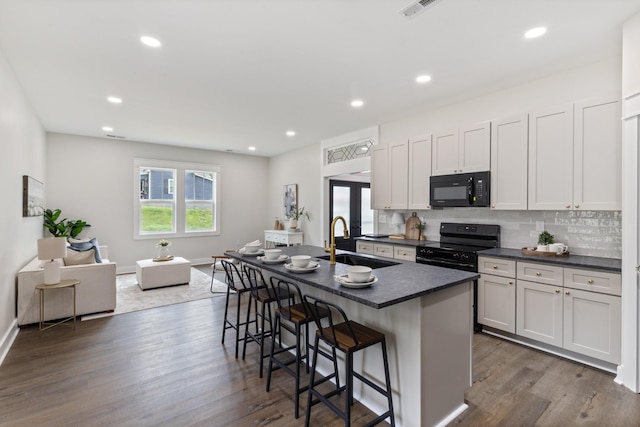 312 N Main St, Dickson, TN 37055 - kitchen featuring black appliances, a sink, dark countertops, a kitchen bar, and a kitchen island with sink