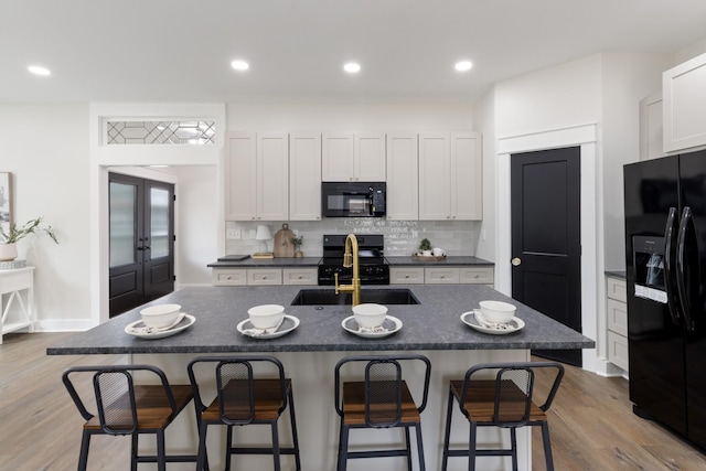 312 N Main St, Dickson, TN 37055 - kitchen with black appliances, dark countertops, a sink, a kitchen bar, and tasteful backsplash