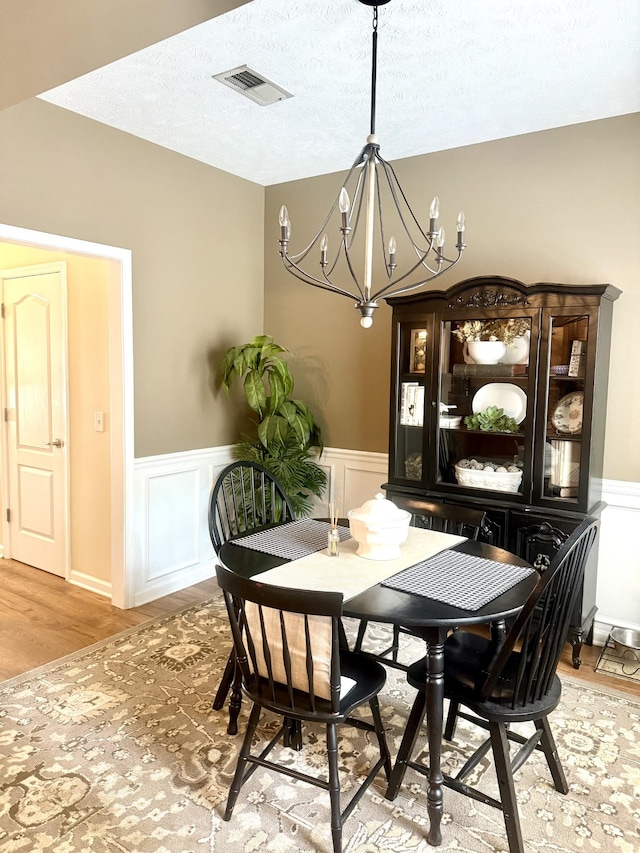 284 Meigs Dr Unit C19, Murfreesboro, TN 37128 - dining area featuring a chandelier, wainscoting, light wood-type flooring, a decorative wall, and a textured ceiling