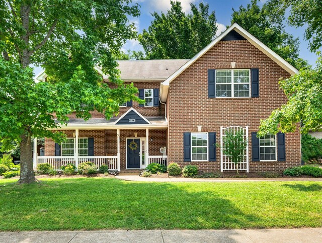 3113 Friars Bridge Pass, Franklin, TN 37064 - view of front of house featuring brick siding, a front yard, a porch, and roof with shingles