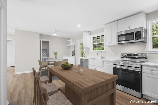 4044 Brick Church Pike, Nashville, TN 37207 - kitchen featuring stainless steel appliances, a sink, white cabinets, light countertops, and light wood-style flooring