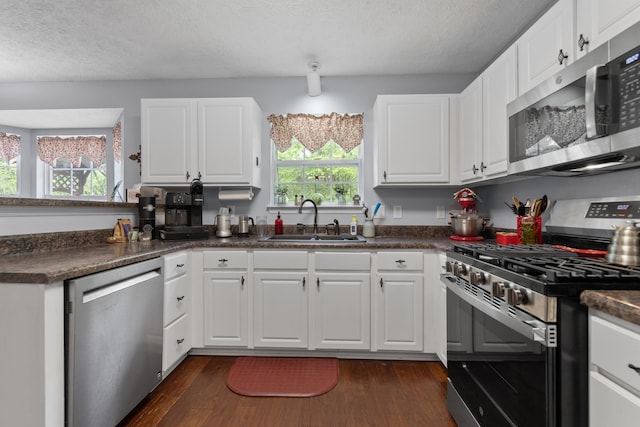 373 Baronswood Dr, Nolensville, TN 37135 - kitchen with appliances with stainless steel finishes, a sink, dark countertops, dark wood-style floors, and white cabinetry