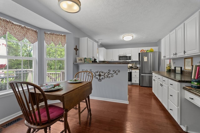 373 Baronswood Dr, Nolensville, TN 37135 - kitchen featuring stainless steel appliances, dark countertops, dark wood finished floors, a textured ceiling, and white cabinetry