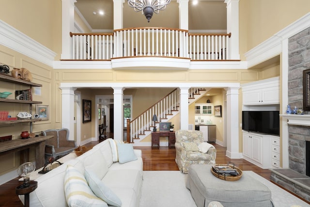 460 Whistler Cv, Franklin, TN 37067 - living area with ornate columns, a stone fireplace, a high ceiling, stairs, and wood finished floors