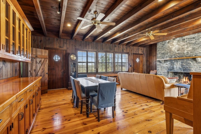 4430 Brush Hill Rd, Nashville, TN 37216 - dining room featuring wood ceiling with exposed beams, a ceiling fan, wooden walls, light wood-style flooring, and a stone fireplace