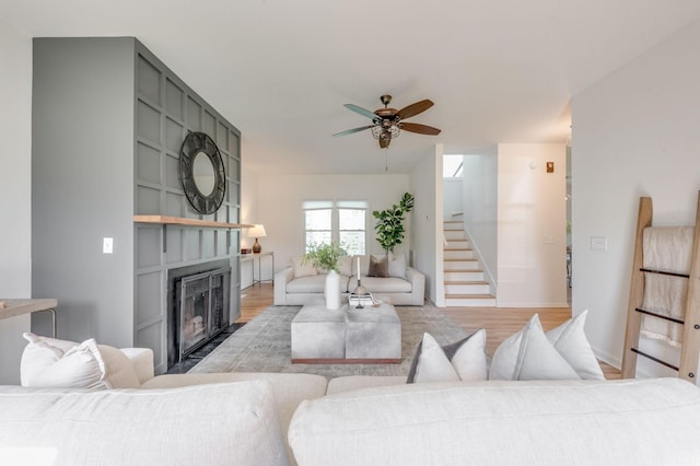 608 Claridge Ct, Franklin, TN 37064 - living area featuring a fireplace with flush hearth, ceiling fan, stairway, light wood-style floors, and baseboards