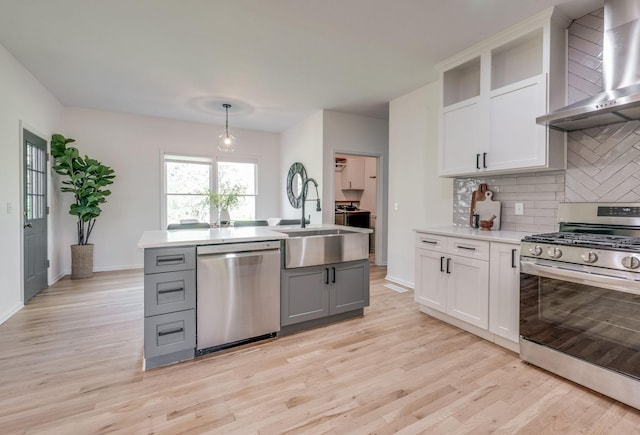 608 Claridge Ct, Franklin, TN 37064 - kitchen with stainless steel appliances, wall chimney range hood, a sink, light wood-style flooring, and backsplash