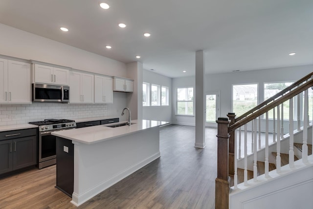 529 Little Penny Dr, Smyrna, TN 37167 - kitchen featuring appliances with stainless steel finishes, a center island with sink, decorative backsplash, light wood finished floors, and recessed lighting