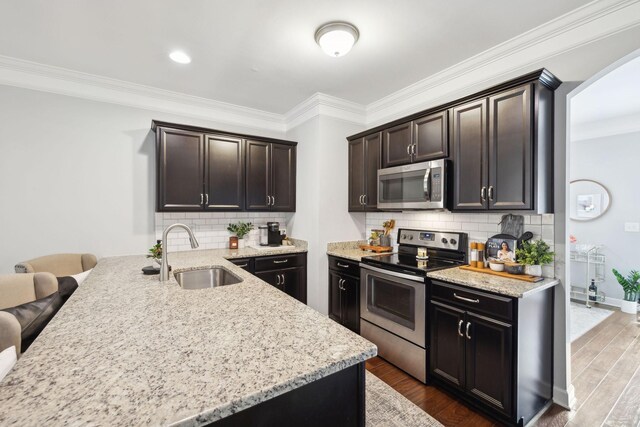 212 Walden Village Ln, Nashville, TN 37210 - kitchen with appliances with stainless steel finishes, a sink, a peninsula, dark brown cabinets, and light stone counters