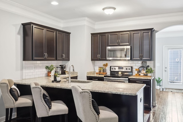 212 Walden Village Ln, Nashville, TN 37210 - kitchen featuring appliances with stainless steel finishes, a sink, arched walkways, dark brown cabinets, and a peninsula
