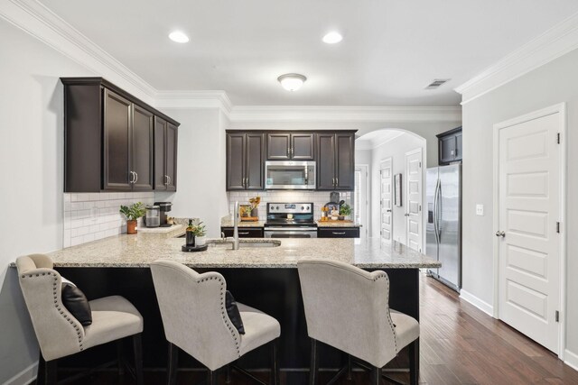 212 Walden Village Ln, Nashville, TN 37210 - kitchen with stainless steel appliances, a peninsula, dark brown cabinetry, arched walkways, and a kitchen bar