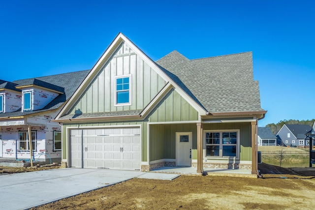 516 Willow Grv Ct, Ringgold, GA 30736 - view of front facade with board and batten siding, a shingled roof, driveway, a garage, and covered porch