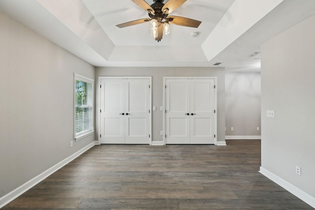 1816 Brentwood Pointe, Franklin, TN 37067 - unfurnished bedroom featuring a tray ceiling, multiple closets, dark wood-style flooring, baseboards, and a ceiling fan