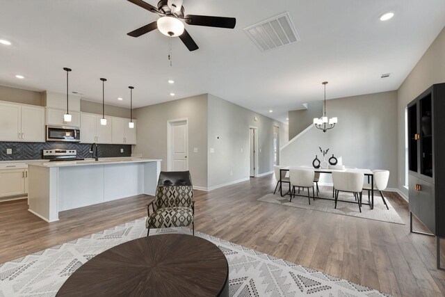1012 Indigo Aly, Brentwood, TN 37027 - kitchen with stainless steel microwave, a center island with sink, range, light wood-type flooring, and recessed lighting
