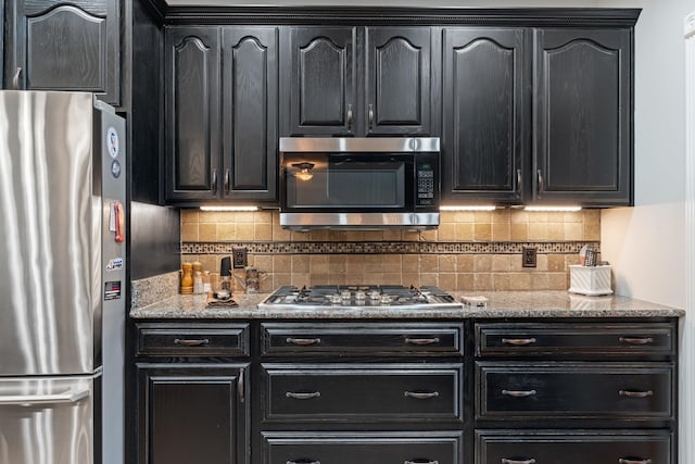1010 Saint Blaise Trl, Gallatin, TN 37066 - kitchen featuring appliances with stainless steel finishes, dark cabinets, decorative backsplash, and light stone counters