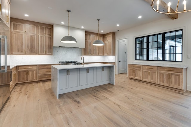 2756 Otterham Dr, Thompsons Station, TN 37179 - kitchen featuring tasteful backsplash, an island with sink, light countertops, light wood-style floors, and a chandelier