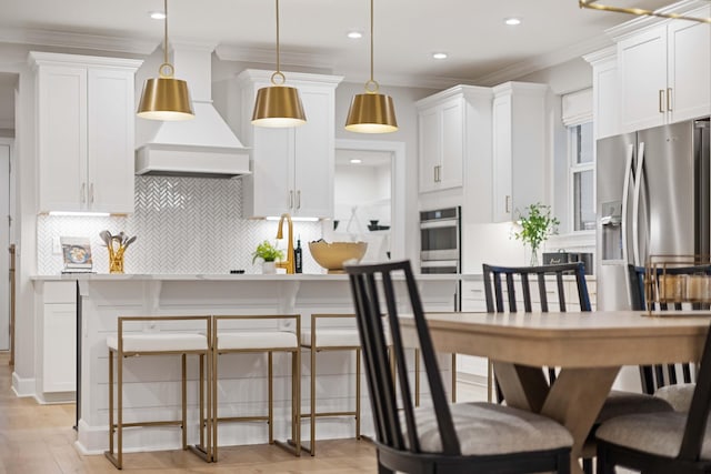 1069 Sycamore Ests, Nashville, TN 37211 - kitchen featuring premium range hood, decorative backsplash, white cabinetry, ornamental molding, and pendant lighting