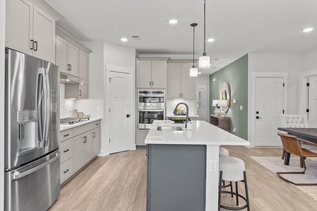2481H Hamilton Ln, Lebanon, TN 37087 - kitchen featuring appliances with stainless steel finishes, a sink, light countertops, decorative backsplash, and light wood finished floors