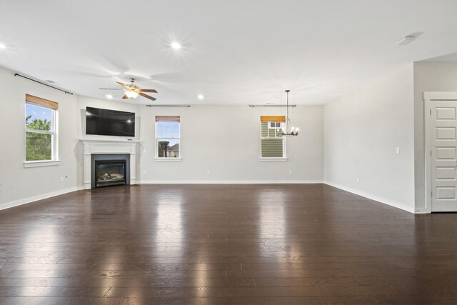 3368 Vinemont Dr, Thompsons Station, TN 37179 - unfurnished living room featuring dark wood-style flooring, a glass covered fireplace, ceiling fan, a chandelier, and recessed lighting