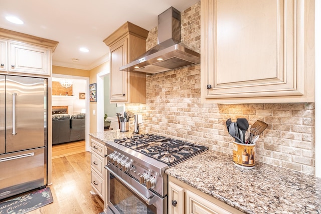 1234 Windsor Dr, Gallatin, TN 37066 - kitchen with high end appliances, wall chimney exhaust hood, light stone countertops, light wood-style flooring, and crown molding