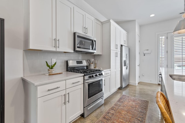 682 James Ave, Nashville, TN 37209 - kitchen with appliances with stainless steel finishes, backsplash, finished concrete floors, baseboards, and white cabinets