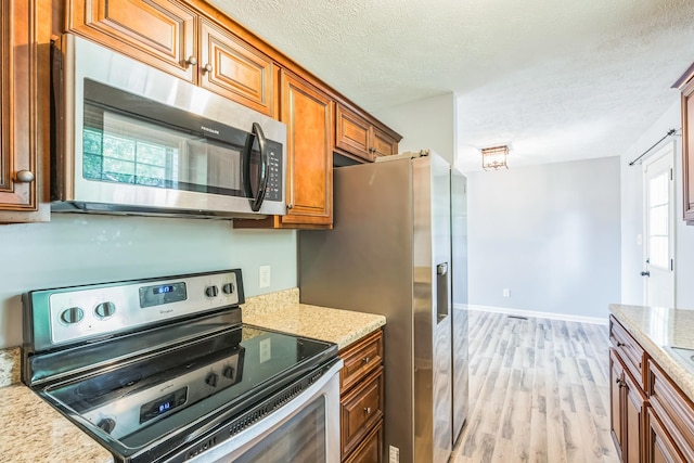 1435 Silver Creek Rd, Lewisburg, TN 37091 - kitchen featuring stainless steel appliances, brown cabinets, light wood-style flooring, a textured ceiling, and baseboards