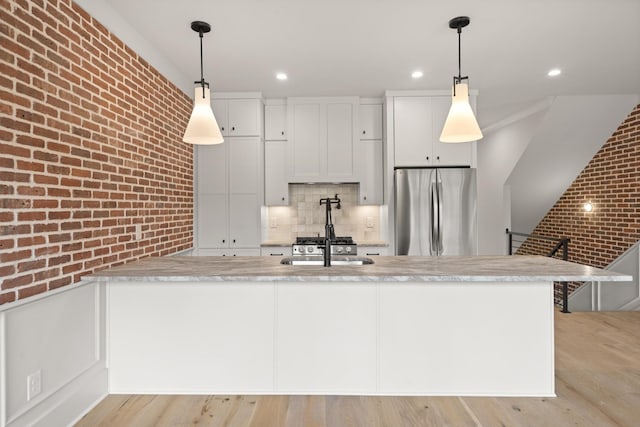 1701 Portland Ave Unit C, Nashville, TN 37212 - kitchen with freestanding refrigerator, light countertops, brick wall, tasteful backsplash, and light wood finished floors