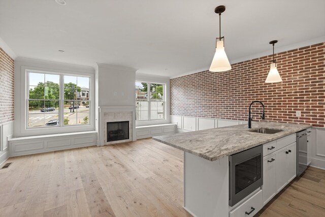 1701 Portland Ave Unit C, Nashville, TN 37212 - kitchen featuring a sink, stainless steel appliances, brick wall, light wood-style floors, and light stone countertops