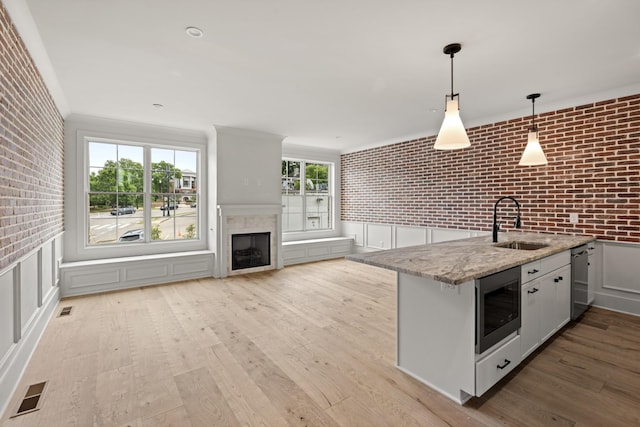 1701 Portland Ave Unit C, Nashville, TN 37212 - kitchen with stainless steel appliances, a sink, brick wall, light wood-type flooring, and decorative light fixtures