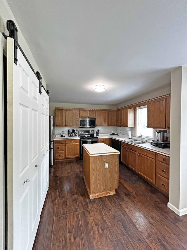 305 Wildwood Dr, Smyrna, TN 37167 - kitchen with stainless steel appliances, a barn door, light countertops, a center island, and dark wood-style flooring