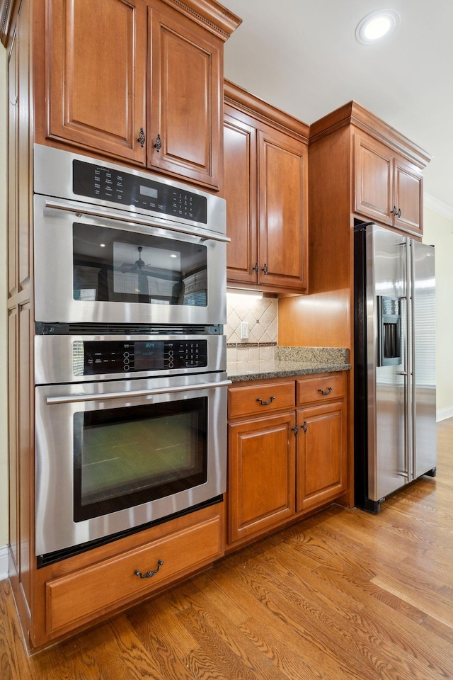 3334 Granite Springs Way, Murfreesboro, TN 37130 - kitchen featuring appliances with stainless steel finishes, light wood-style flooring, brown cabinetry, backsplash, and ornamental molding