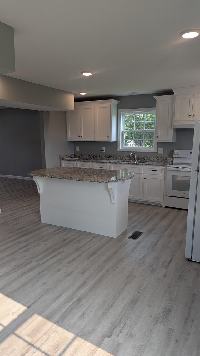 171 Ashmore Rd, Summertown, TN 38483 - kitchen featuring white appliances, light wood-type flooring, a breakfast bar, white cabinetry, and recessed lighting