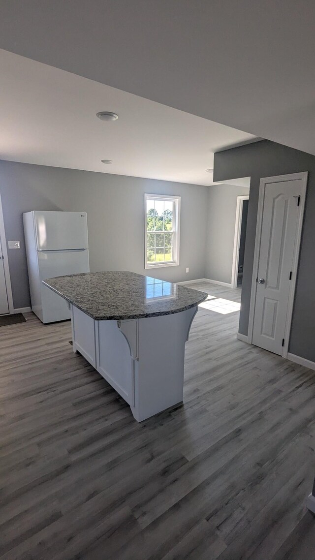 171 Ashmore Rd, Summertown, TN 38483 - kitchen with freestanding refrigerator, wood finished floors, a center island, stone counters, and white cabinetry