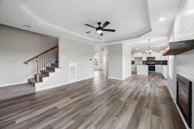 2586 Rafiki Dr, Clarksville, TN 37042 - unfurnished living room with a tray ceiling, a ceiling fan, ornamental molding, a chandelier, and recessed lighting