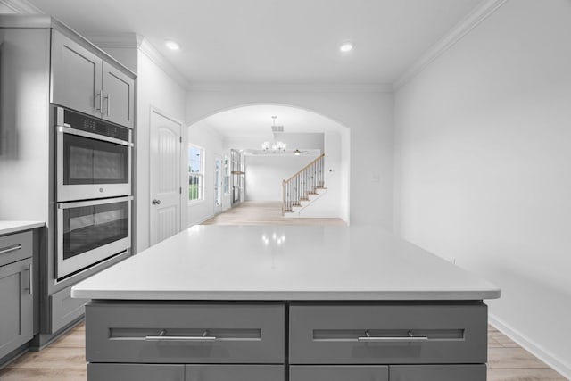 2582 Rafiki Dr, Clarksville, TN 37042 - kitchen featuring gray cabinetry, stainless steel double oven, arched walkways, ornamental molding, and light countertops